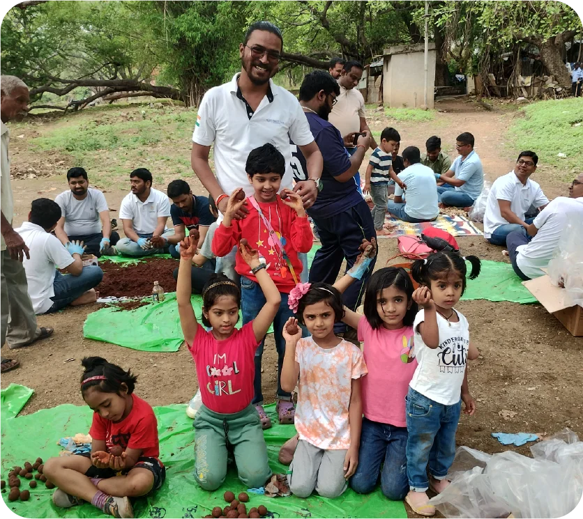 Large group participating in a seedball workshop under trees